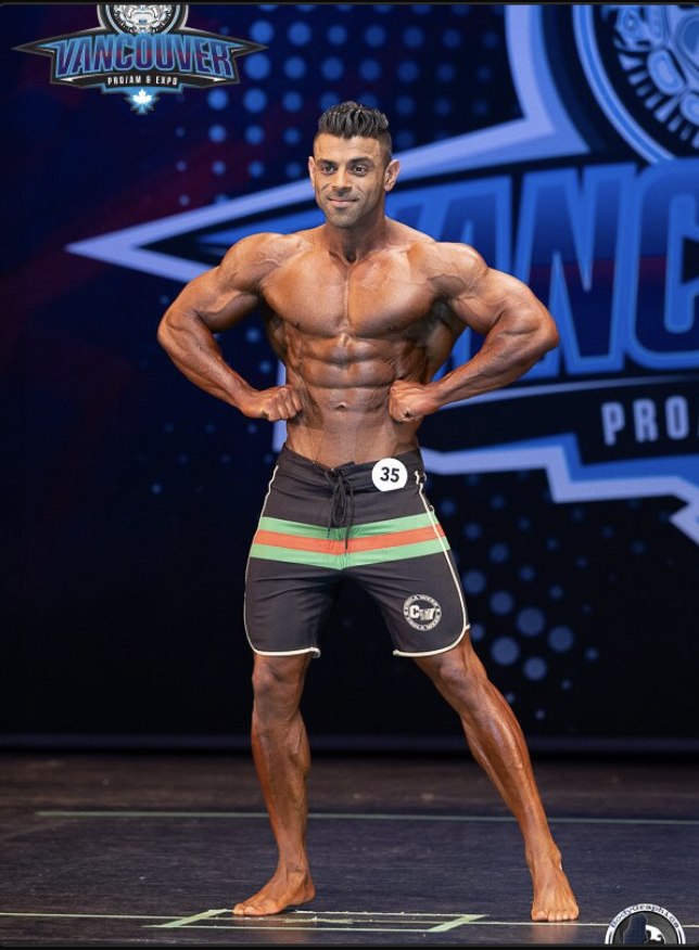Gurjinder Virk, IFBB Pro bodybuilder and co-founder of The Whole Bowl, posing on stage at Vancouver Pro